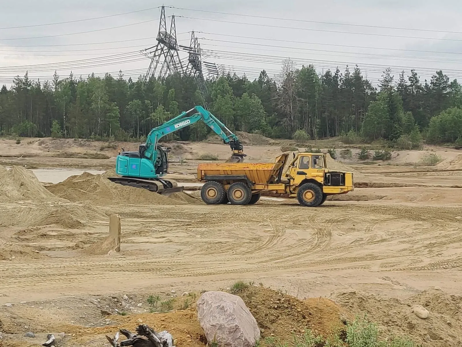 Grävmaskin lastar en dumper på en anläggningsplats