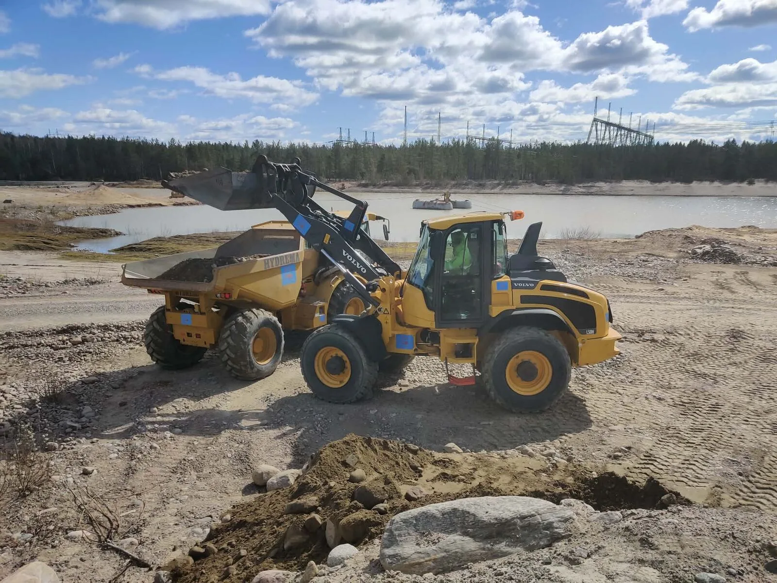 Hjullastare och dumper på en grusplan vid en sjö