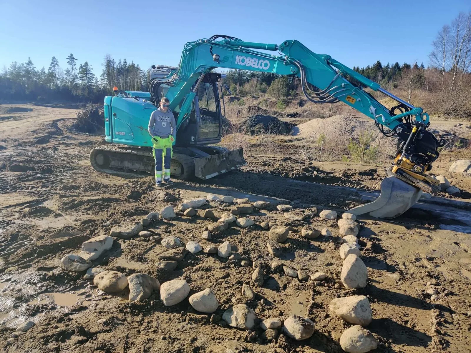 Grävmaskin på en övningsplats med instruktör bredvid
