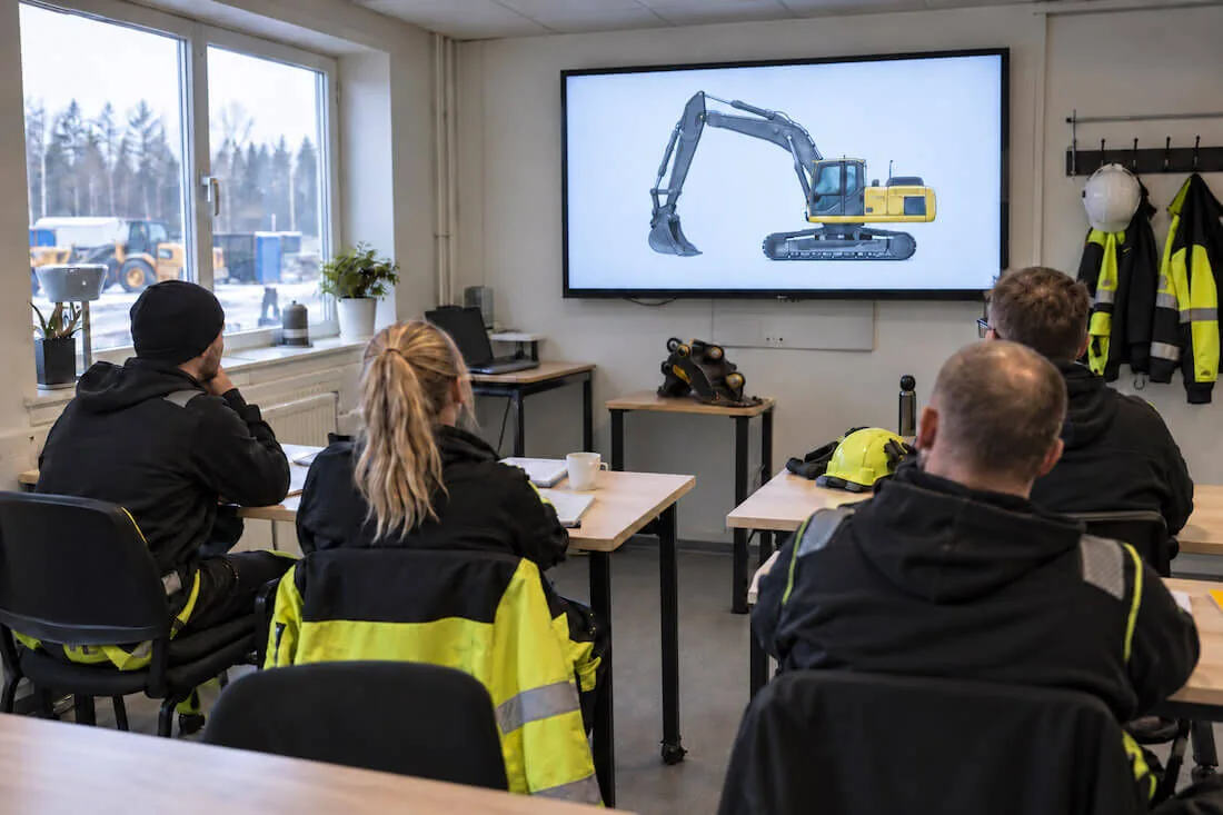 Deltagare i ett klassrum under en teorilektion om grävmaskiner